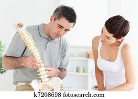 Chiropractor and patient looking at a model of a spine Chiropractor and patient looking at a model of a spine