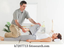Chiropractor stretching young woman's leg Chiropractor stretching young woman's leg