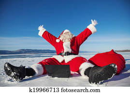 Santa Claus sitting on snow glad news in the laptop
