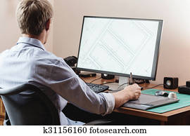 Graphic designer using digital tablet and computer in office or home Graphic designer using digital tablet and computer in office or home