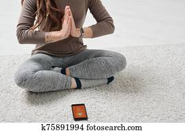 Active woman sitting with her legs crossed and hands put together by chest