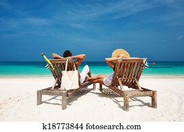 Couple in white relax on a beach at Maldives