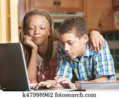 Mother and teen son work in kitchen on laptop Mother and teen son work in kitchen on laptop