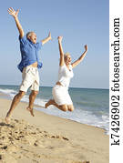 Senior Couple Enjoying Beach Holiday Jumping In Air