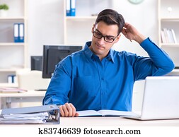 Handsome businessman employee sitting at his desk in office Handsome businessman employee sitting at his desk in office