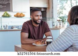 Smiling young African man enjoying his date in a cafe