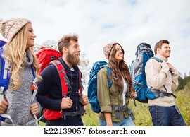 group of smiling friends with backpacks hiking