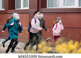 Children students in medical masks leave the school. Children students in medical masks leave the school.