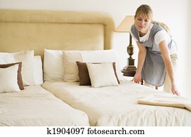 Maid making bed in hotel room Maid making bed in hotel room