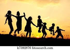 Silhouette, group of happy children playing on meadow, sunset, summertime