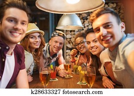 happy friends with smartphone taking selfie at bar happy friends with smartphone taking selfie at bar