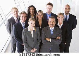 Group of co-workers standing in office space smiling (high key)