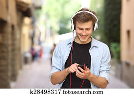 Guy walking and using a smart phone with headphones