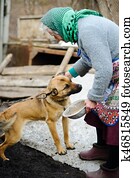 The elderly countrywoman plays with a puppy.
