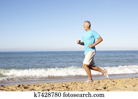 Senior Man In Fitness Clothing Running Along Beach