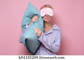 Young caucasian woman wearing sleep mask during sleeping holding a pillow Young caucasian woman wearing sleep mask during sleeping holding a pillow