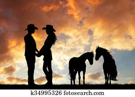 couple of cowboys with horse at sunset couple of cowboys with horse at sunset