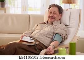 Elderly man measuring blood pressure