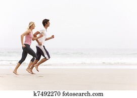 Young Couple Running Along Winter Beach