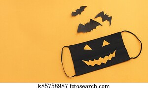 Evil face mask, bat and spider decorations on orange background with copy space. Stay safe Evil face mask, bat and spider decorations on orange background with copy space. Stay safe