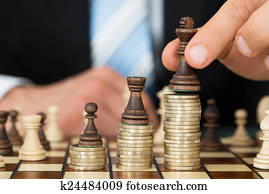 Businessman Placing Chess Pieces On Stacked Coins
