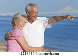 Happy Senior Couple Walking Pointing on Beach