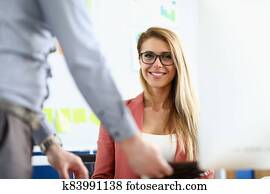 The woman with glasses sits in the office and smiles The woman with glasses sits in the office and smiles