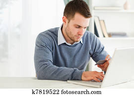 Male entering credit card information in his laptop