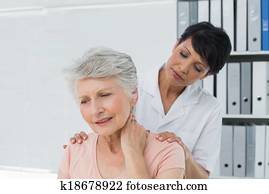 Chiropractor looking at senior woman with neck pain Chiropractor looking at senior woman with neck pain