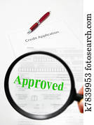 a credit application and magnifying glass with Approved text
