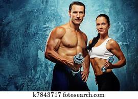 Athletic man and woman with a dumbells.