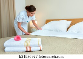 Maid making bed in hotel room Maid making bed in hotel room