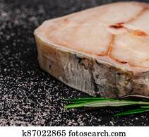 Raw Catfish steak on shale board with rosemary and salt