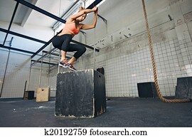 Female athlete is performing box jumps at gym Female athlete is performing box jumps at gym
