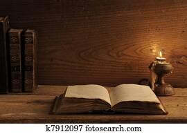 old book on a wooden table by candlelight