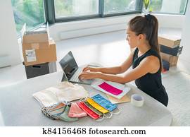 Online small business entrepreneur woman working remote from home on laptop selling cloth mask handmade from fabric on ecommerce app for COVID-19 Online small business entrepreneur woman working remote from home on laptop selling cloth mask handmade from fabric on ecommerce app for COVID-19