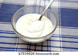 Yoghurt in a bowl with spoon on table