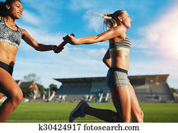 Female relay team passing the baton