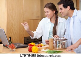 smiling couple using a laptop to cook pictures k7976468