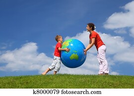 Mother with  son play an inflatable globe in  day-time stand  on  grass