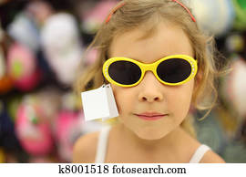 ritratto, di, piccola ragazza, tentando, occhiali da sole, con, giallo, orlo, in, negozio, poco profondo, profondità, di, fuoco