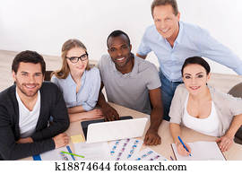 Strong business team. Top view of group of business people in casual wear sitting together at the table and smiling at camera