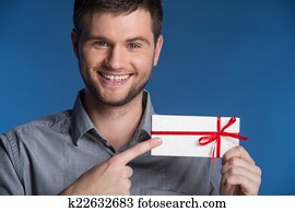 Present gift in hands of smiling man. closeup on happy man standing on blue background and pointing