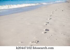 Human footprints on white sand beach