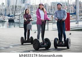 Adult friends posing near segways on shore Adult friends posing near segways on shore