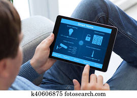 man in jeans holding tablet computer with smart home
