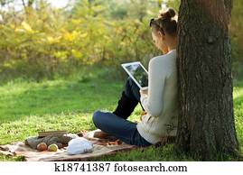 Distance education. Sitting woman using ipad during stroll outdoors Distance education. Sitting woman using ipad during stroll outdoors