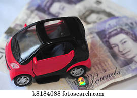 Black and red car over a lot of British Pound Sterling bills isolated on white (selective focus).