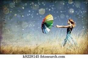 Redhead girl with umbrella at windy grass meadow. Photo in old color image style. Redhead girl with umbrella at windy grass meadow. Photo in old color image style.