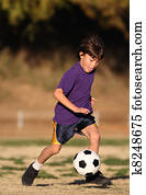 Boy playing soccer in late afternoon light